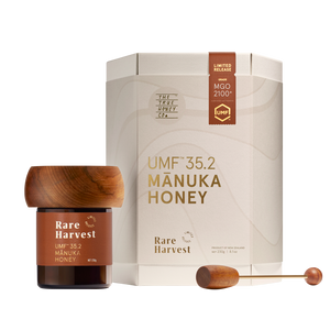 Manuka honey MGO 2100+ jar with wooden lid and packaging on a white background