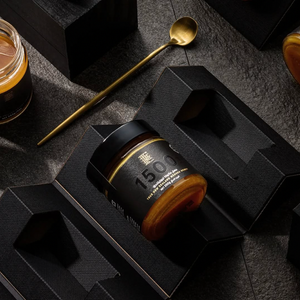 Jar of honey in a textured gift box with a spoon and another jar.