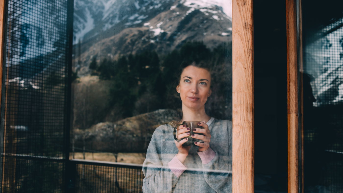 lady standing at a window looking out at a snowy mountain