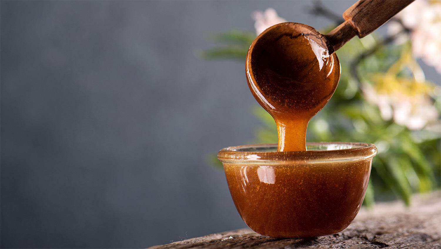 Honey dripping from a wooden dipper into a bowl
