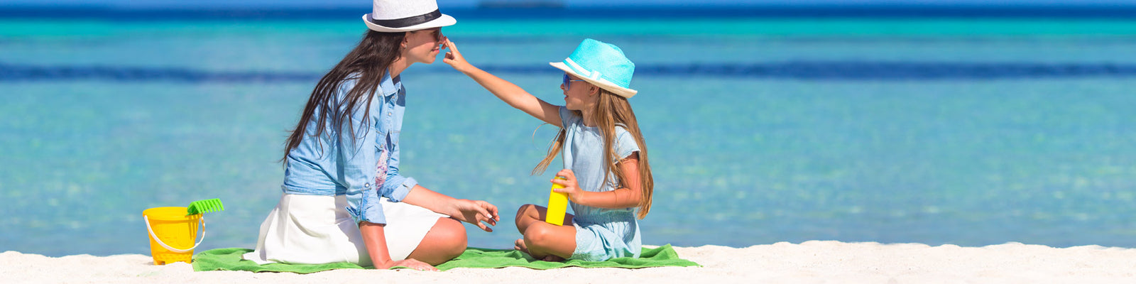 Mother and daughter at beach applying natural sunscreen with Manuka Honey - Aftersun skincare