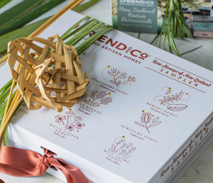 Honey packaging with floral elements and a brand name on a white surface