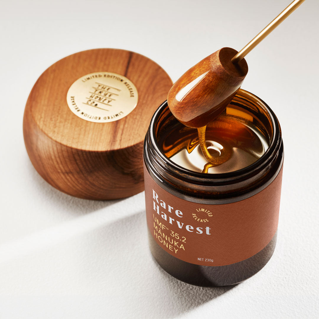 Jar of honey with a wooden dipper, labeled 'Rare Harvest', on a white background.