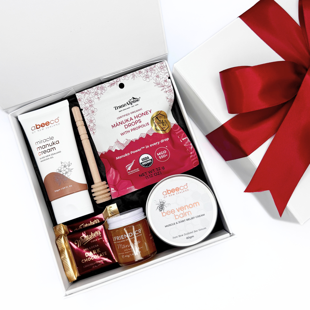 Gift set with Manuka Honey products and a red ribbon on a white background