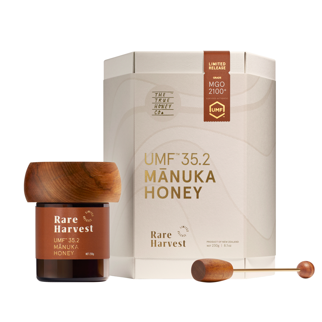 Manuka honey MGO 2100+ jar with wooden lid and packaging on a white background