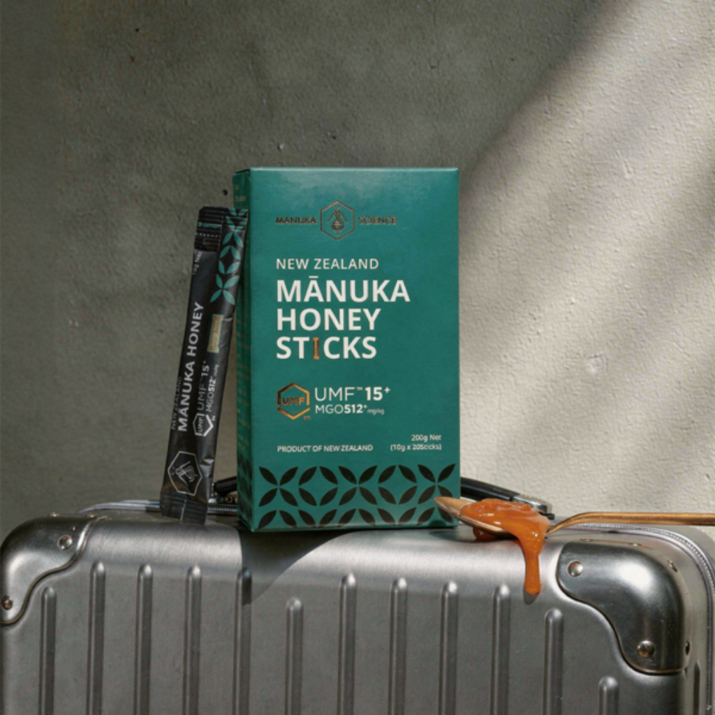 Mânuka Honey Sticks by Manuka Science, featuring a dark green box of New Zealand manuka honey sticks next to a single black stick pack, set against a plain white background.