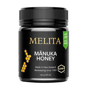A black jar of Melita Mánuka Honey with a black ribbed lid, featuring gold and white text and a green UMF badge on a white background.