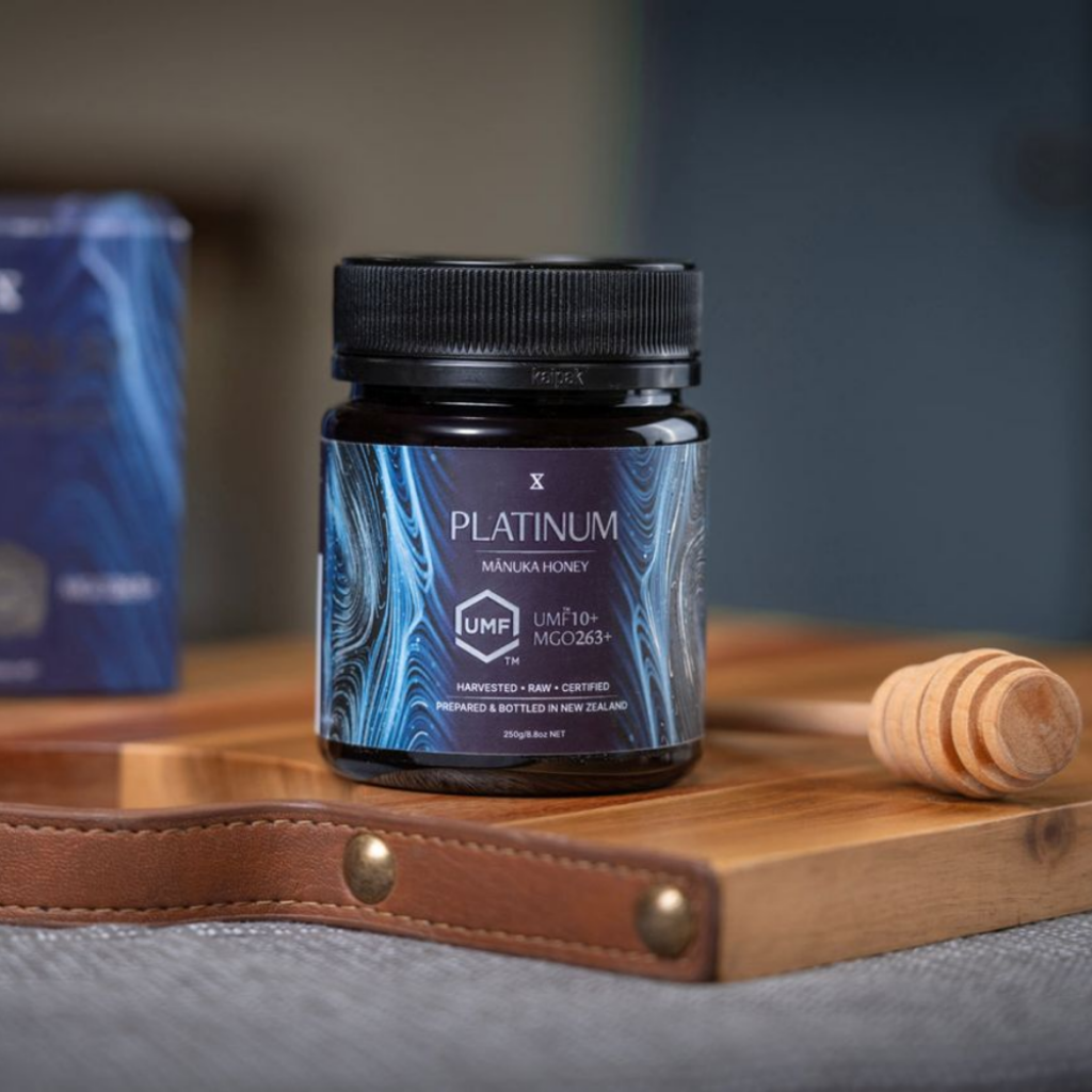 Manuka Honey jar with blue label and black lid on a white background