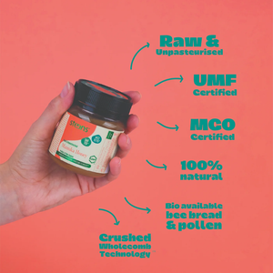 Hand holding a jar of honey with certification text on a pink background
