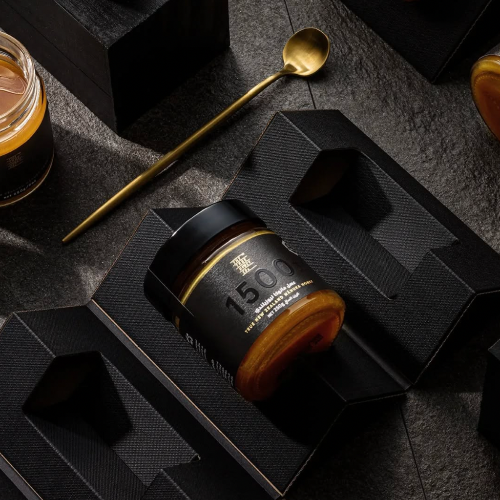 Jar of honey in a textured gift box with a spoon and another jar.