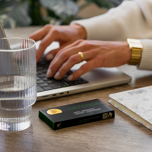 Person using a laptop with a box of DEFENCE lozenges on a desk.