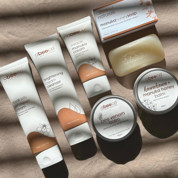 Collection of abeeeco skincare products including creams, balm, and soap on a textured surface.
