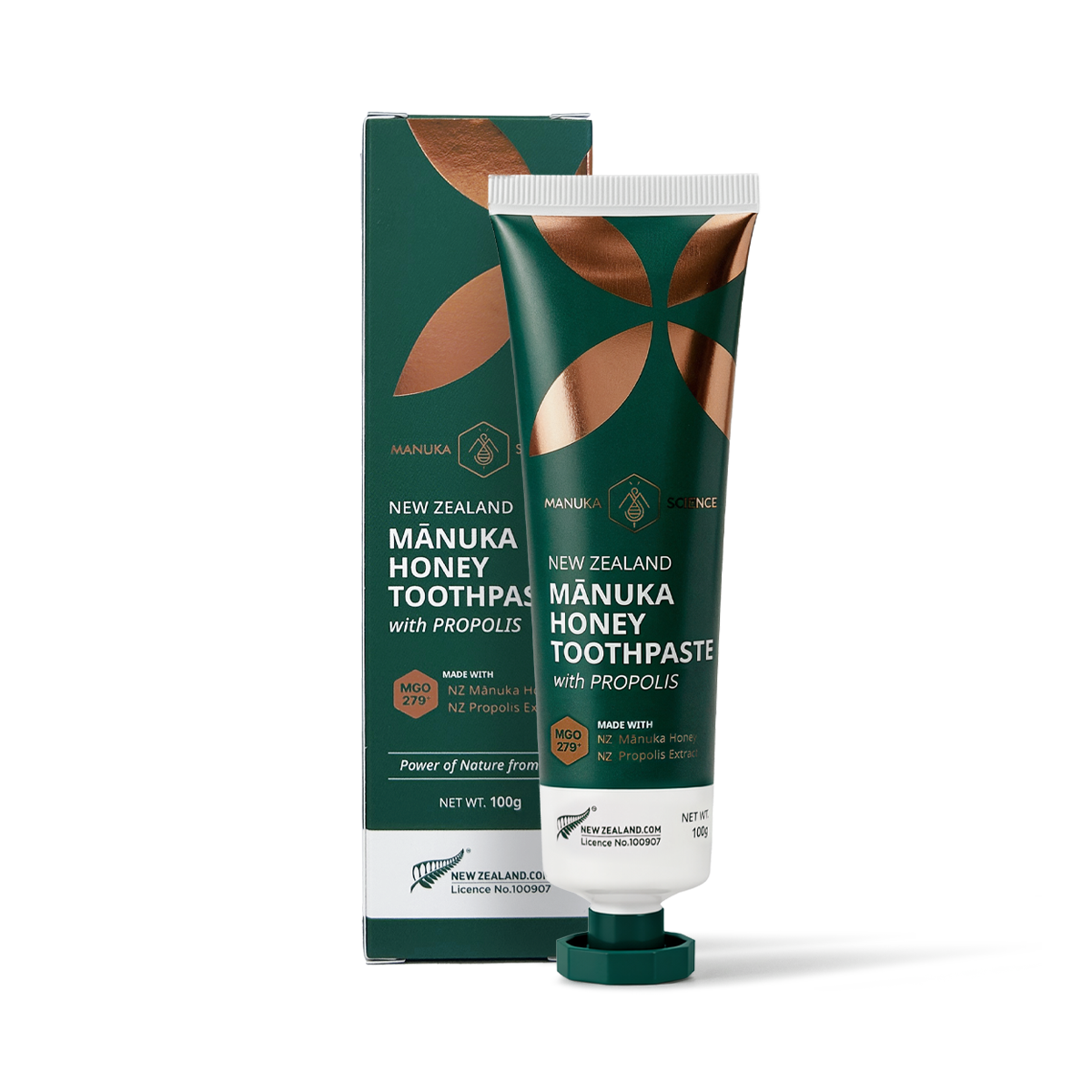 A tube and box of Manuka Honey Toothpaste with Propolis, shown on a clean white background. The packaging features a dark green color with metallic copper leaf designs and white text.